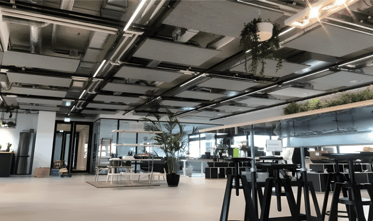 PET-vilt plafondeilanden boven werkzones in een open kantoor, ter ondersteuning van indeling in verschillende werkzones.